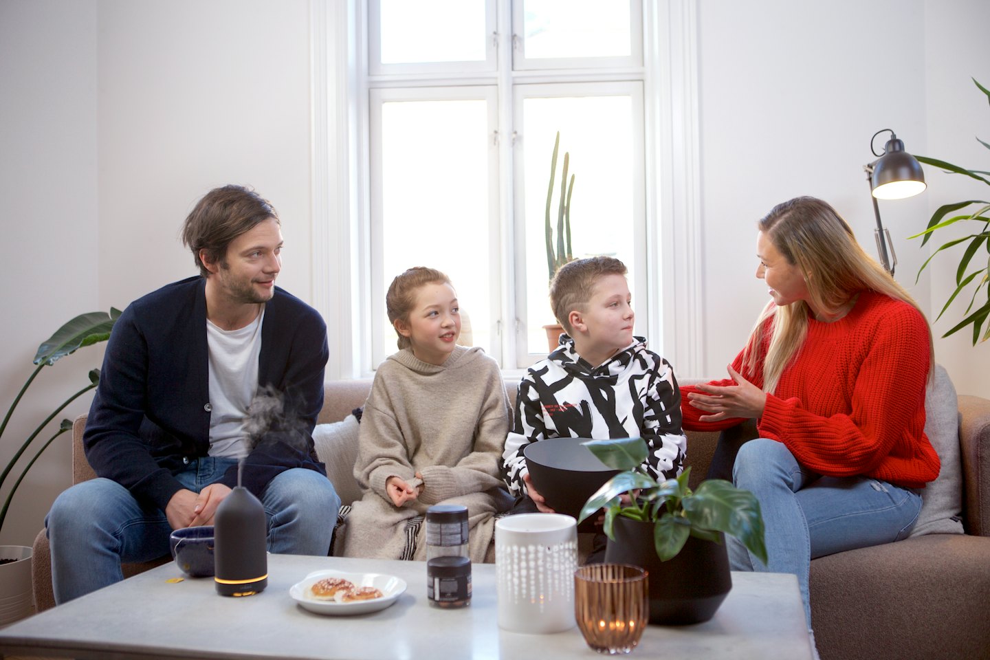 A family sits on a sofa talking in the living room.