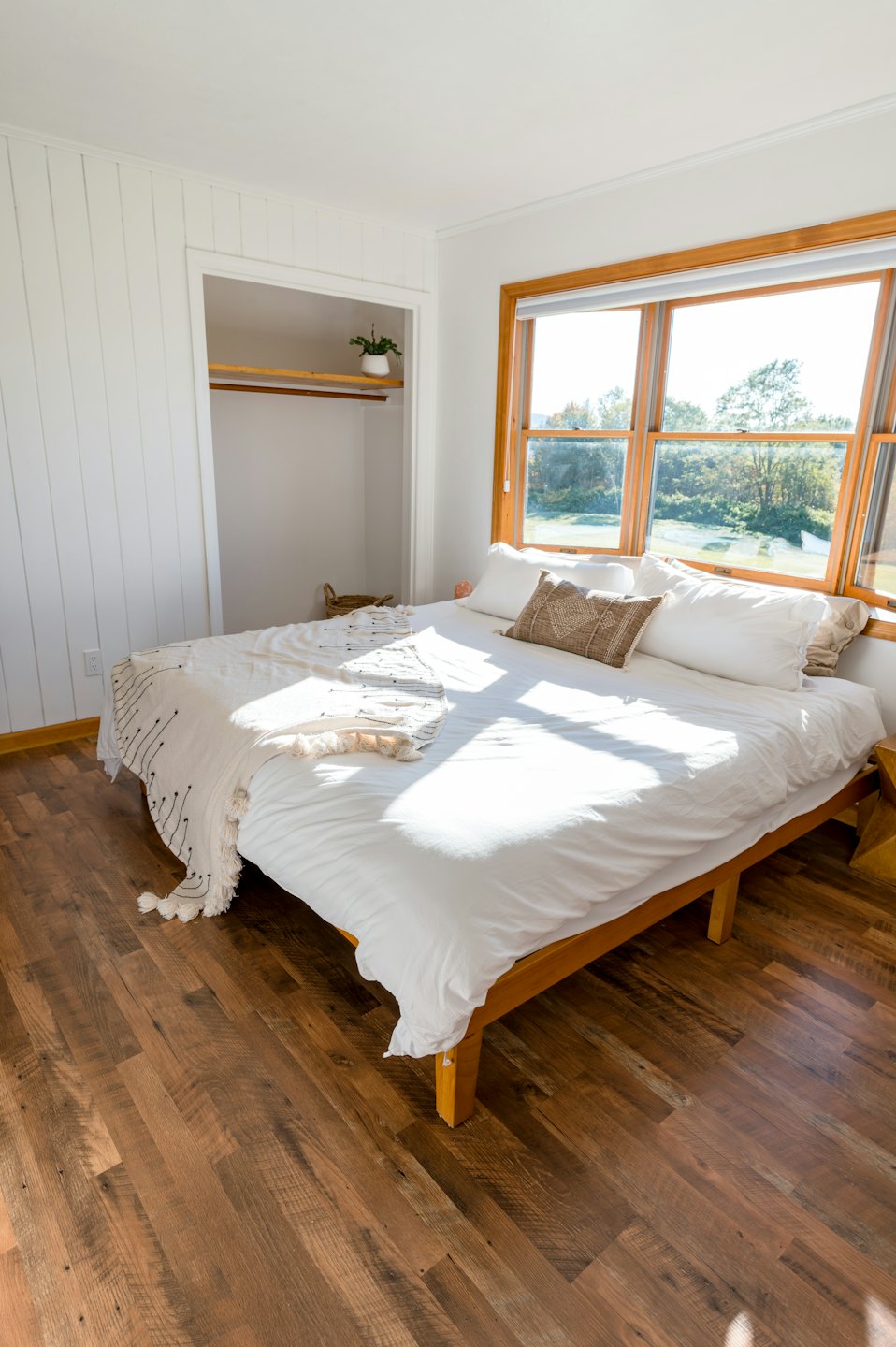 Sunlit bedroom with wooden bed and white linens.